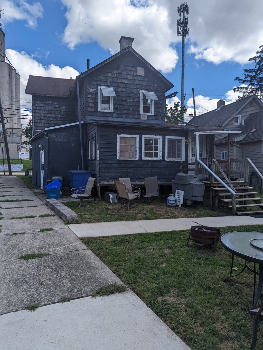 an old house with chairs and a table in the yard