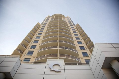 A tall building with a white facade and a large circular logo on the bottom.