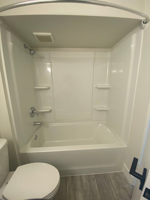 A white toilet is next to a bathtub in a small bathroom.