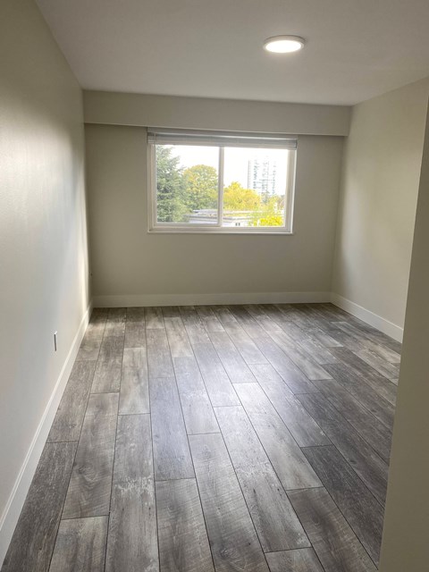 A room with a window and wooden flooring.