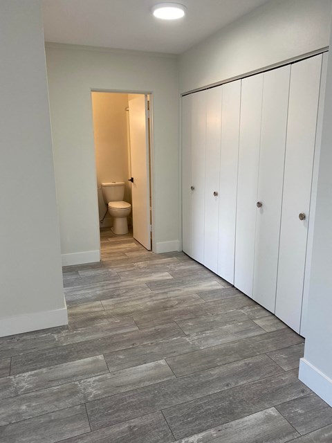 A bathroom with a toilet and a row of white cupboards.