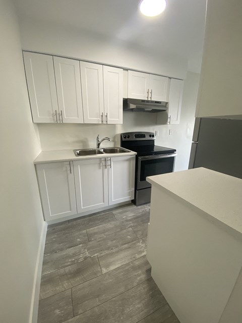 an empty kitchen with white cabinets and black appliances