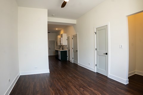 A room with white walls and wood flooring with a white door and a white cabinet.