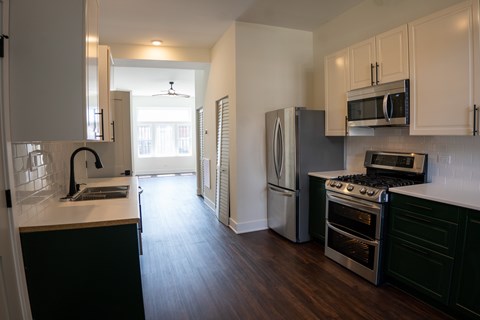 A kitchen with a black counter top and stainless steel appliances.
