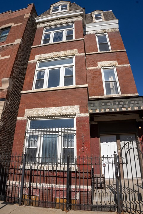 A red brick building with a black iron fence in front.