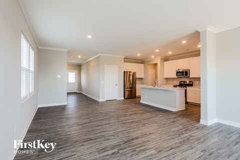 an open kitchen and living room with white cabinets and wood flooring