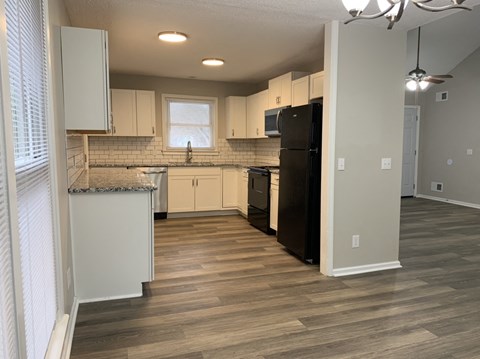 a kitchen with white cabinets and a black refrigerator