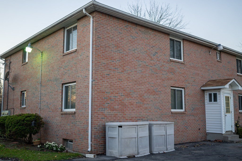 the side of a brick house with two storage bins