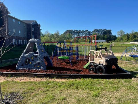 A playground with a train and a rock climber.