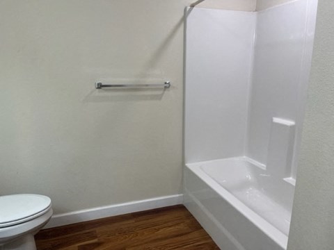 A white toilet sits next to a white bathtub in a small bathroom.