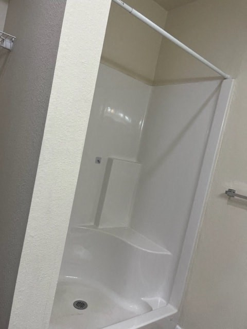 A white bathroom with a white shower stall.