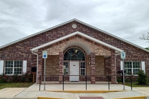 A brick building with a white door and a sign on the sidewalk.