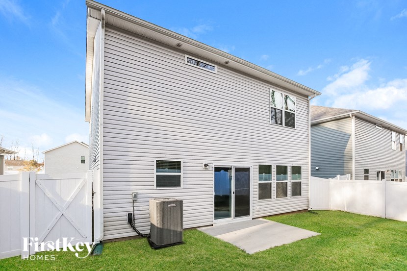 A house with a grey siding and a white fence is for sale.