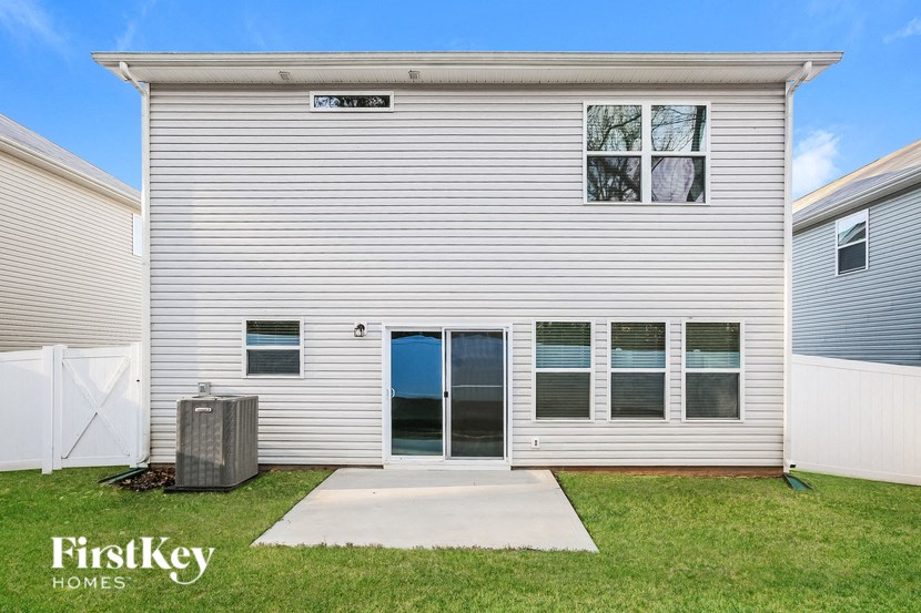 A house with a grey siding and a white fence is for sale.