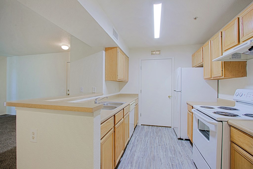 an empty kitchen with wood cabinets and white appliances