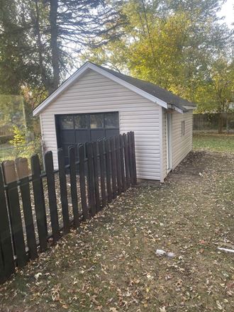 a small shed with a fence in front of it