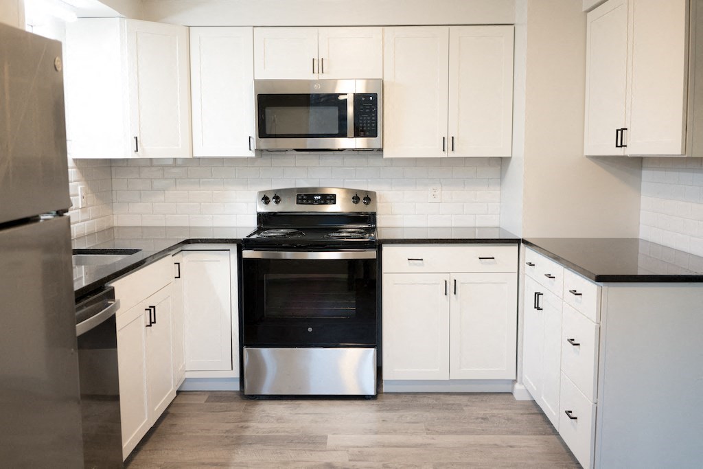 a kitchen with white cabinets and a stove and a microwave