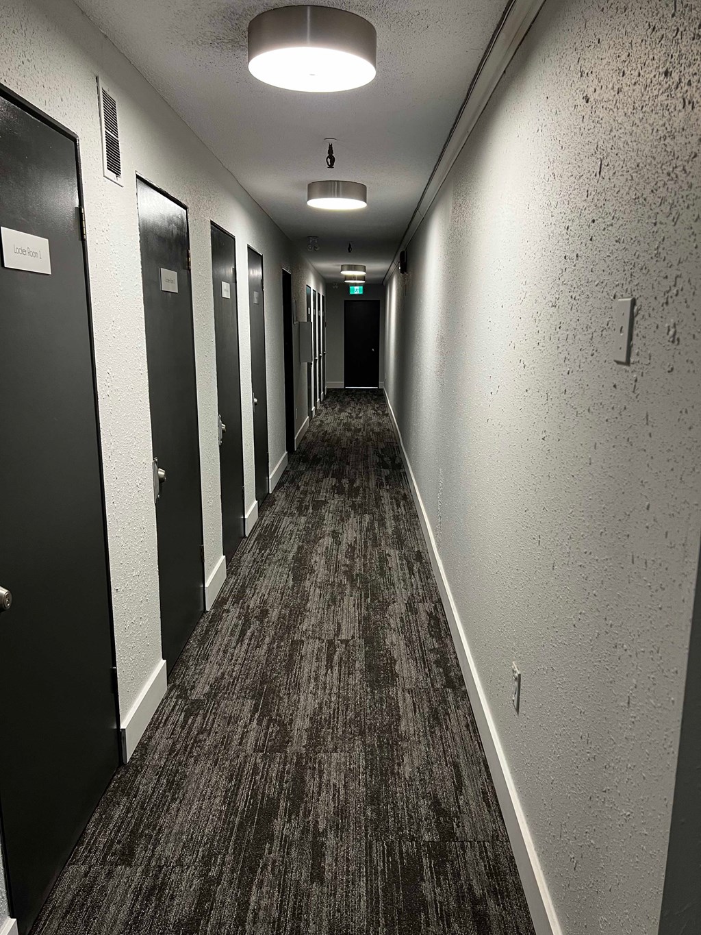 A long hallway with doors on the left and a light at the end.