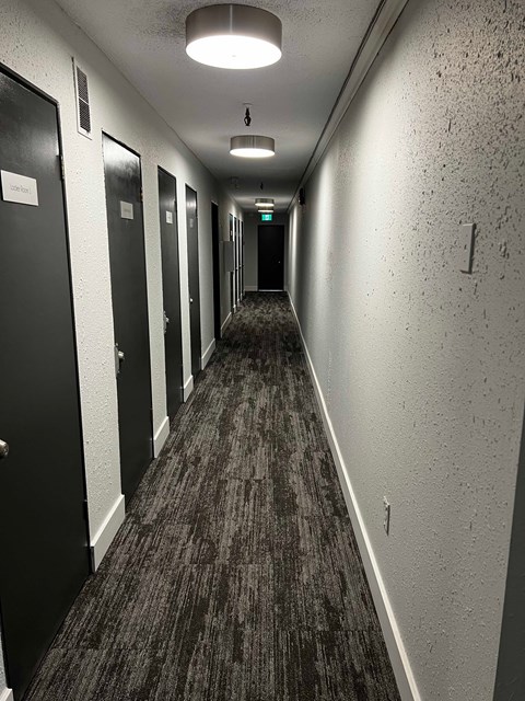 A long hallway with doors on the left and a light at the end.
