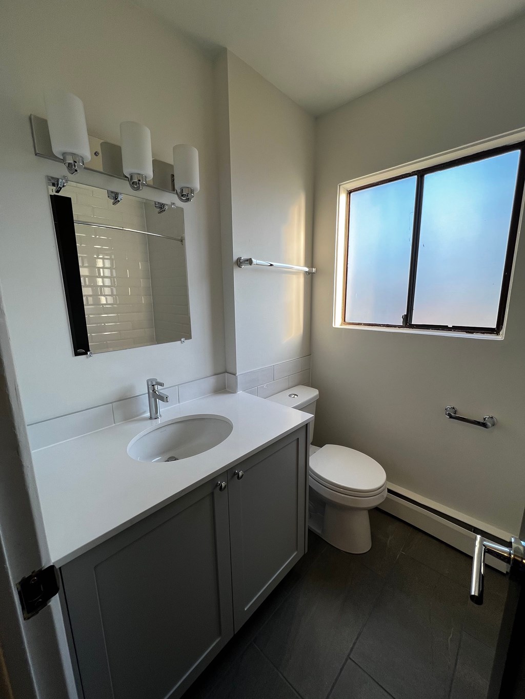 A bathroom with a sink, toilet, and a window.