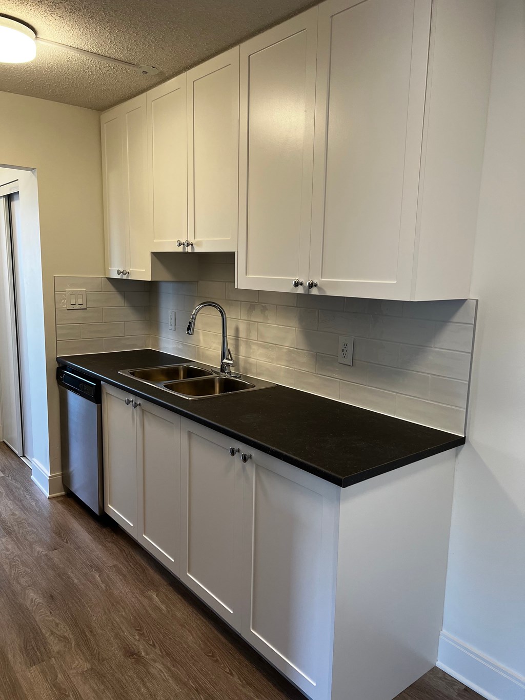 A kitchen with white cabinets and a black countertop.