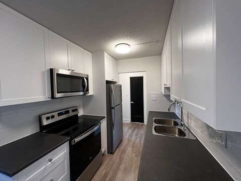 A kitchen with black countertops and white cabinets.