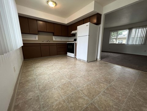an empty kitchen with a refrigerator and a window