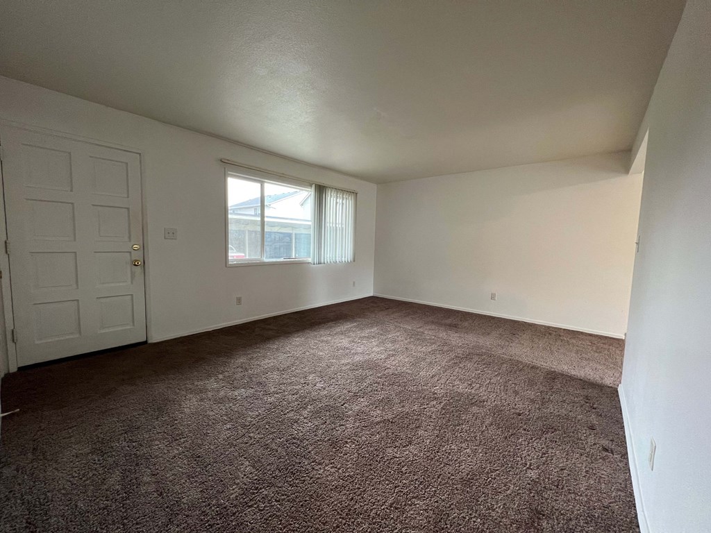 an empty living room with carpet and a white door