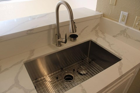a stainless steel sink with a chrome faucet in a white counter top