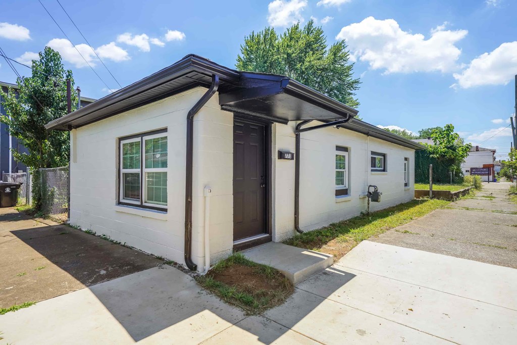 a small white house with a black roof and a sidewalk
