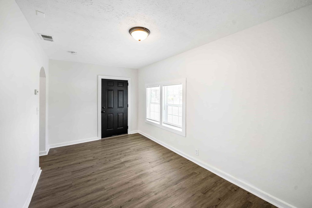 an empty living room with white walls and a black door