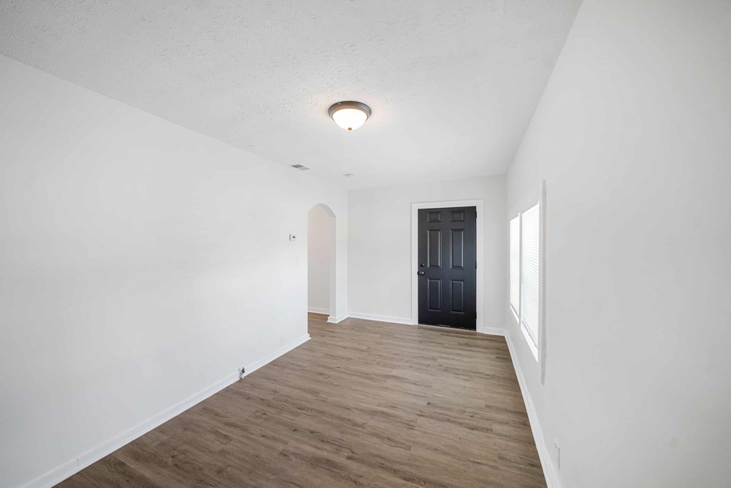 a living room with white walls and a black door     and a