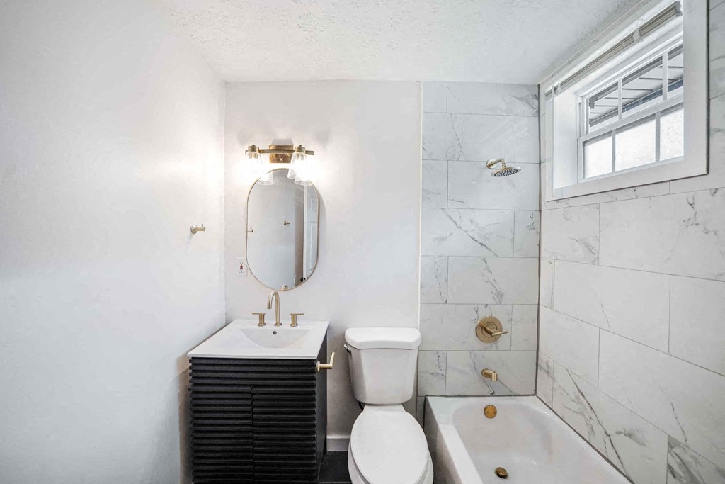 a bathroom with a toilet sink and tub and a mirror