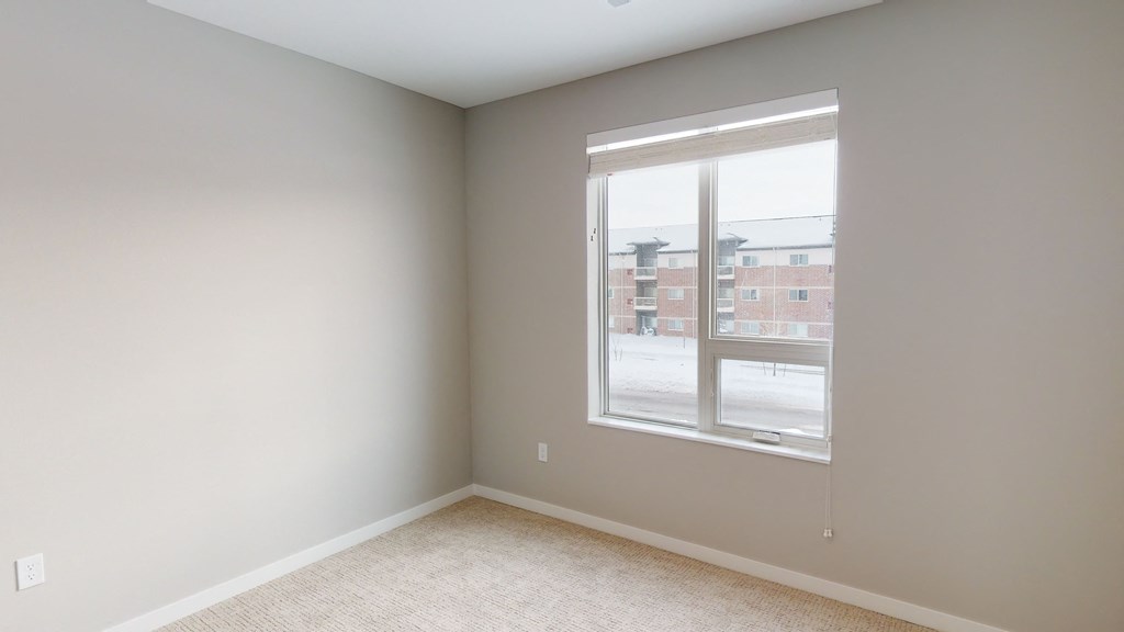an empty room with a large window and carpeting