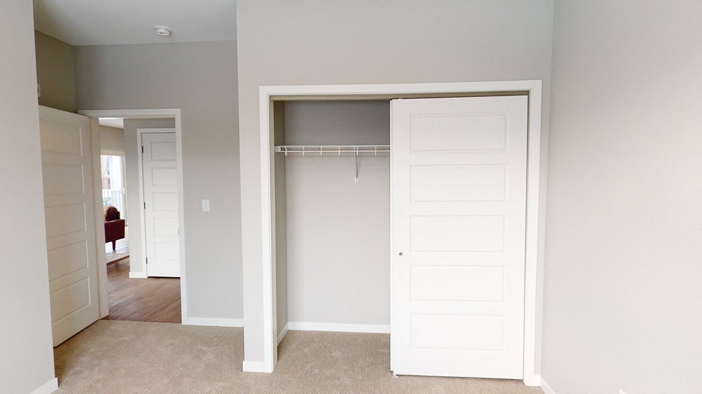 an empty bedroom with a closet with a white door