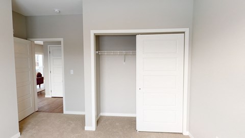 an empty bedroom with a closet with a white door