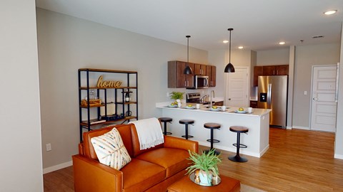 a living room with an orange couch in front of a kitchen
