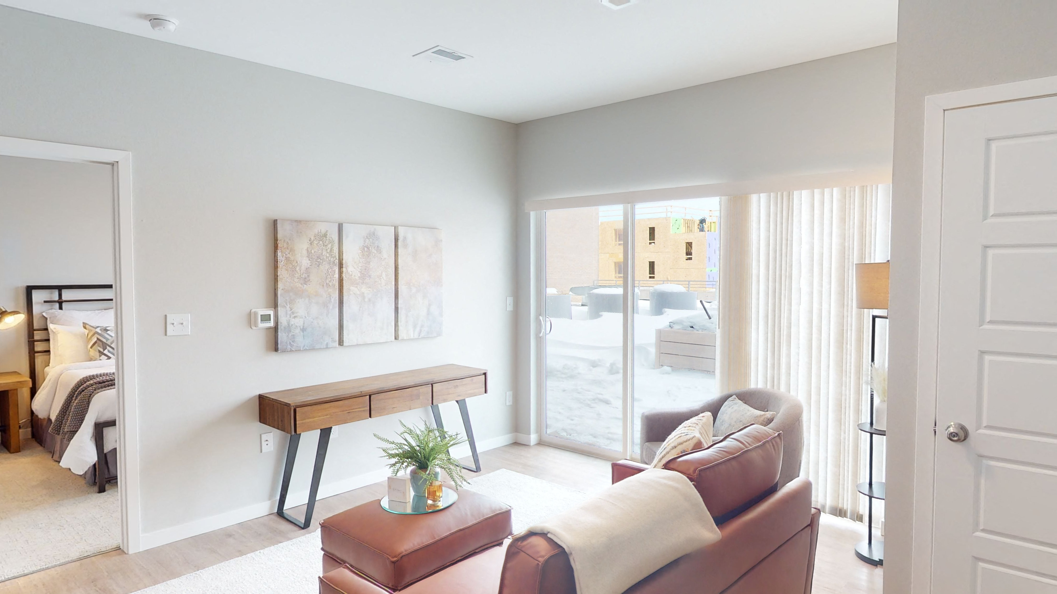 a living room with a couch and a desk and a door to a bedroom
