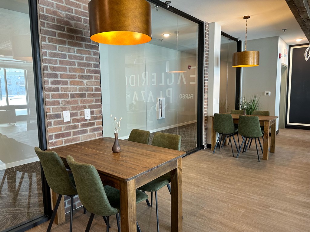 a dining room with a wooden table and chairs and a brick wall