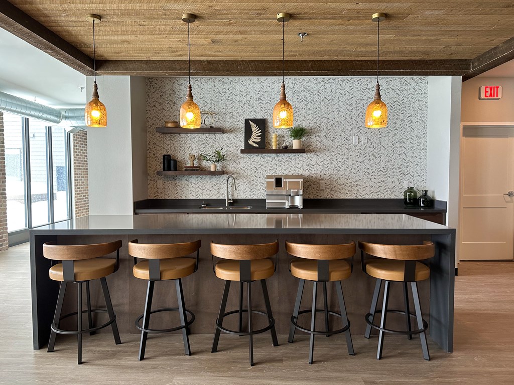 a kitchen with wooden stools in front of a counter with lamps and a counter