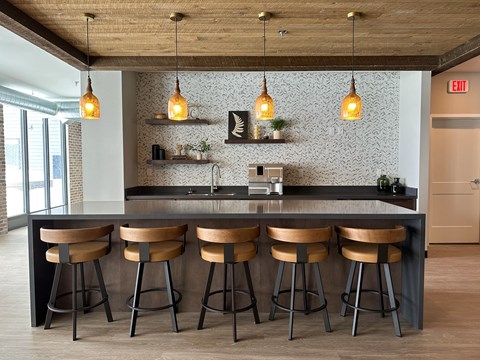a kitchen with wooden stools in front of a counter with lamps and a counter