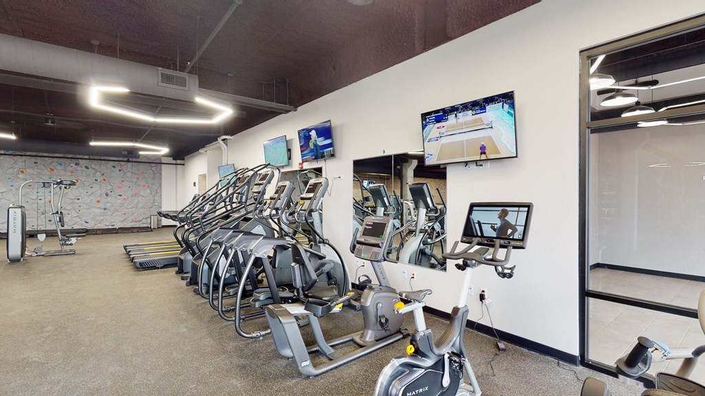 a gym with cardio equipment and weights on the wall