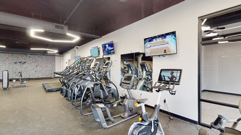 a gym with cardio equipment and weights on the wall