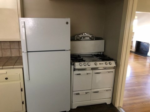 A white refrigerator is in a kitchen next to a white stove.