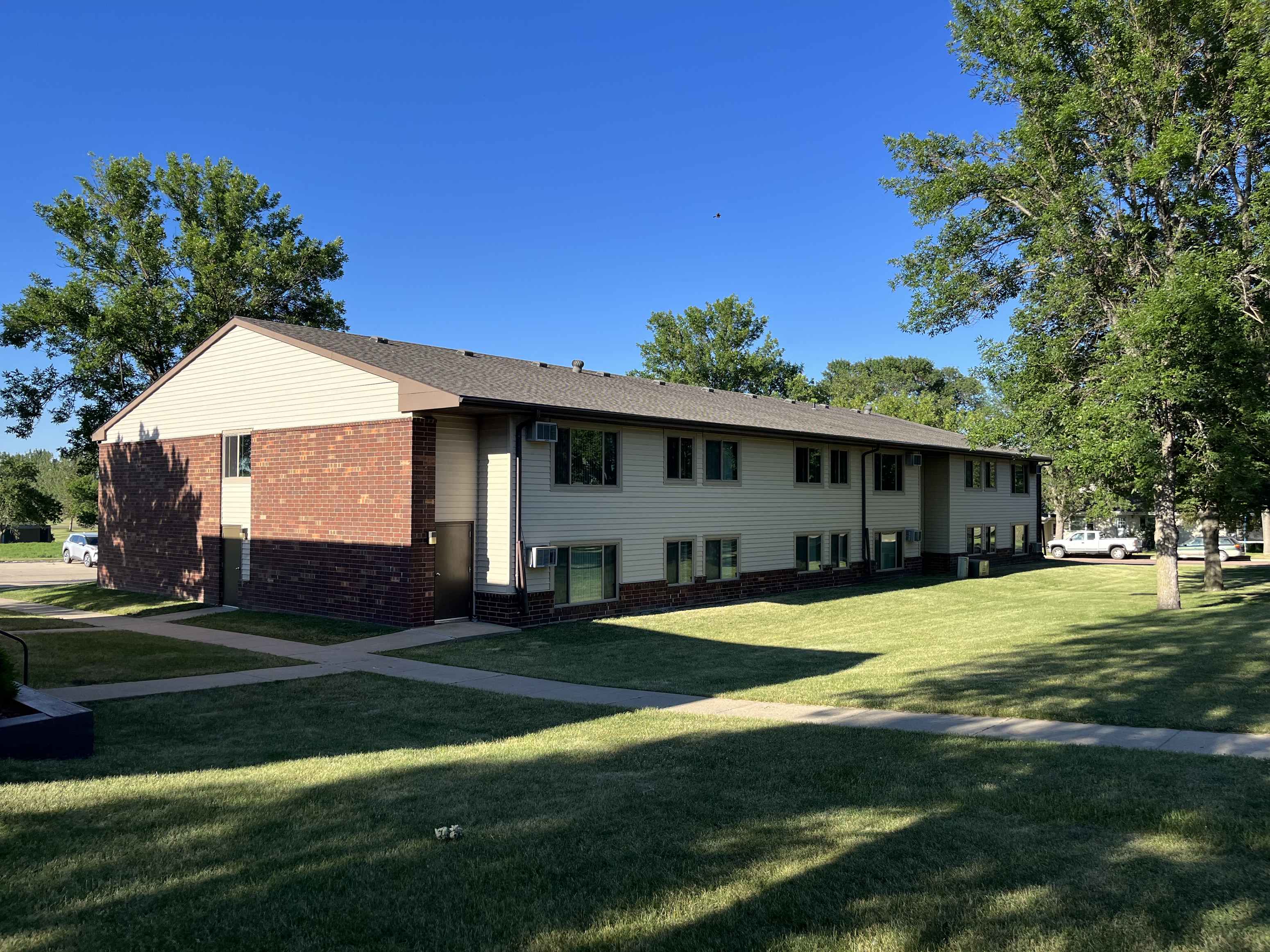 a white house with a lawn and trees