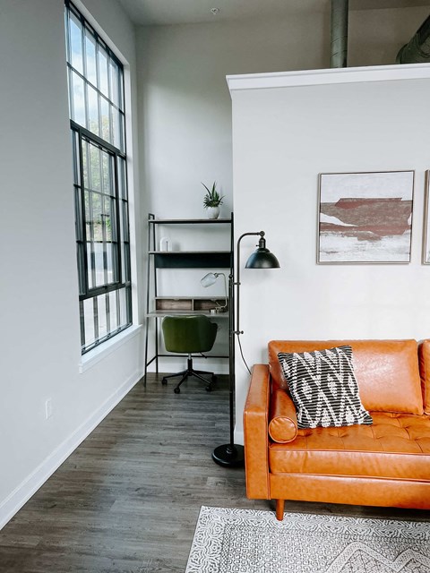 a living room with a orange couch and a desk