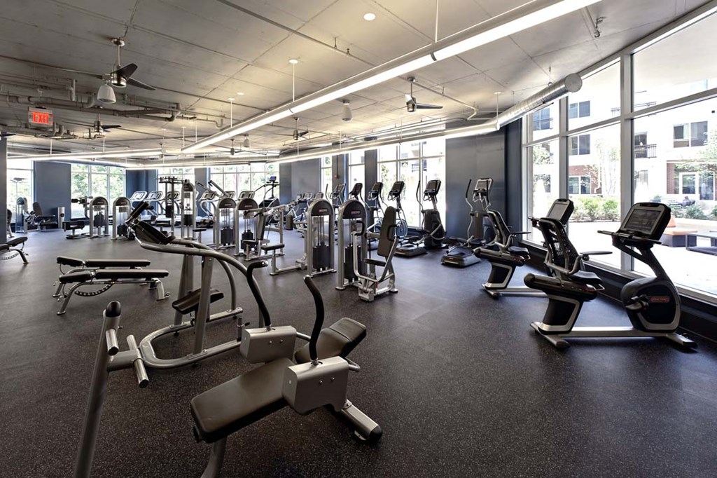 a gym with weights and cardio equipment in a building with windows