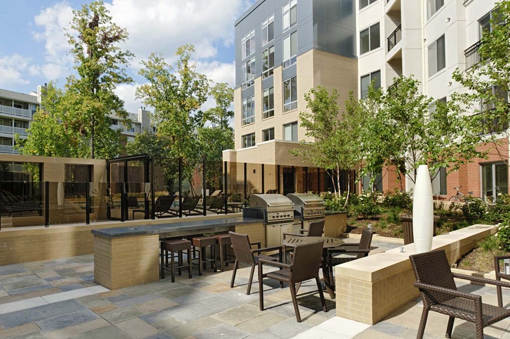a patio with tables and chairs in front of an apartment building