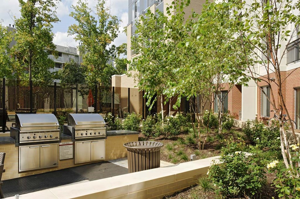 two grills in a courtyard with trees and a building