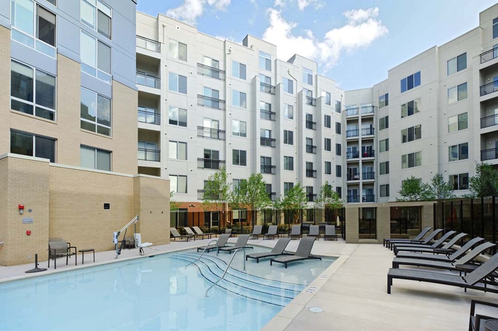 an apartment building with a swimming pool and lounge chairs